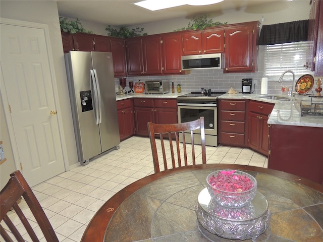 kitchen featuring stainless steel appliances, backsplash, light tile patterned floors, and sink