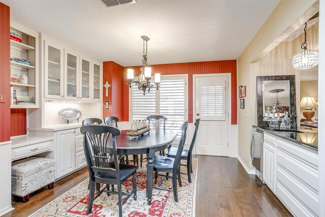 dining room with washer / clothes dryer, an inviting chandelier, dark wood-type flooring, and a textured ceiling