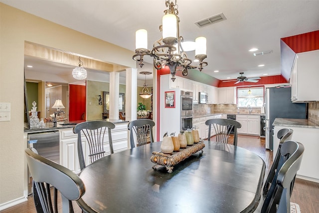 dining area with ceiling fan with notable chandelier, dark wood-type flooring, and sink