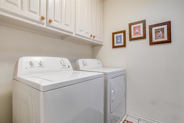 washroom with cabinets, light tile patterned floors, and washing machine and clothes dryer