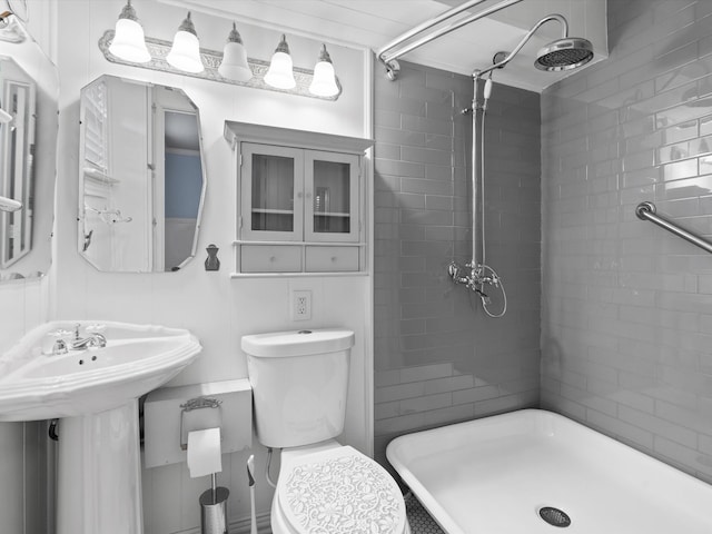 bathroom featuring a tile shower, toilet, and sink