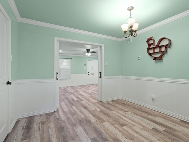 empty room with ceiling fan with notable chandelier, light hardwood / wood-style floors, and ornamental molding