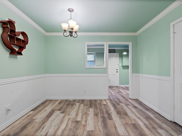 spare room with light wood-type flooring, crown molding, and a chandelier