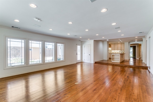 unfurnished living room featuring hardwood / wood-style floors and crown molding