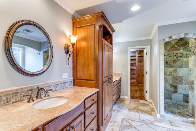 bathroom with vanity, crown molding, and tiled shower