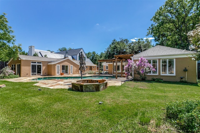 back of house featuring a lawn, a patio, and a swimming pool with hot tub