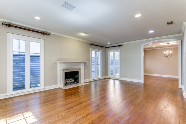 unfurnished living room featuring an inviting chandelier, light wood-type flooring, and ornamental molding