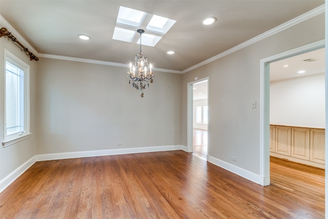 empty room featuring an inviting chandelier, ornamental molding, hardwood / wood-style floors, and a skylight