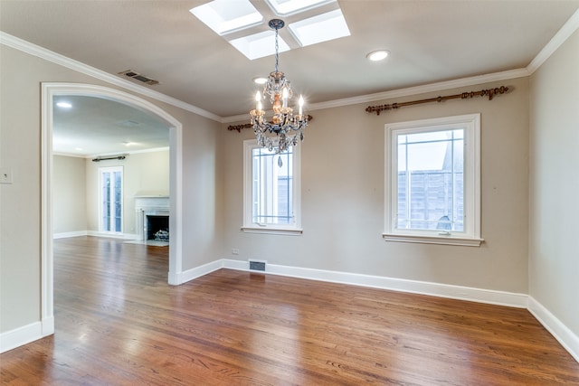 unfurnished room with ornamental molding, an inviting chandelier, a skylight, and hardwood / wood-style flooring