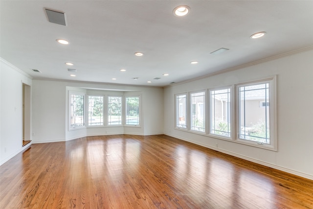 spare room featuring light wood-type flooring and crown molding