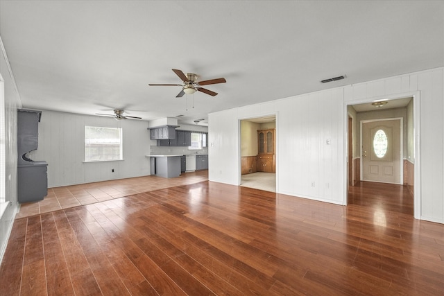 unfurnished living room featuring wood-type flooring, ceiling fan, and plenty of natural light