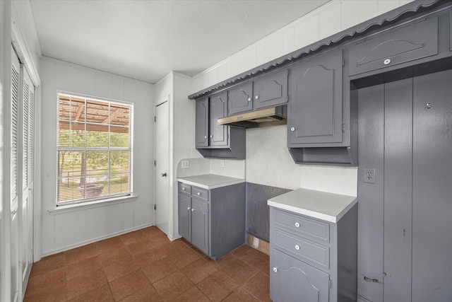 kitchen with a textured ceiling, dark tile patterned flooring, and gray cabinetry