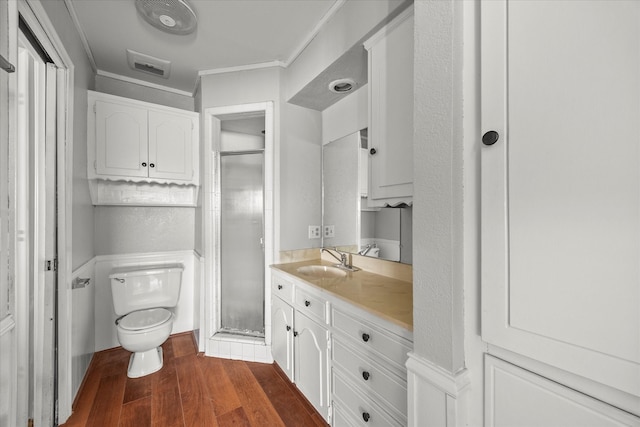 bathroom with vanity, crown molding, hardwood / wood-style floors, a shower with door, and toilet