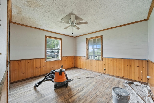 workout area featuring ornamental molding, light hardwood / wood-style floors, a textured ceiling, and ceiling fan