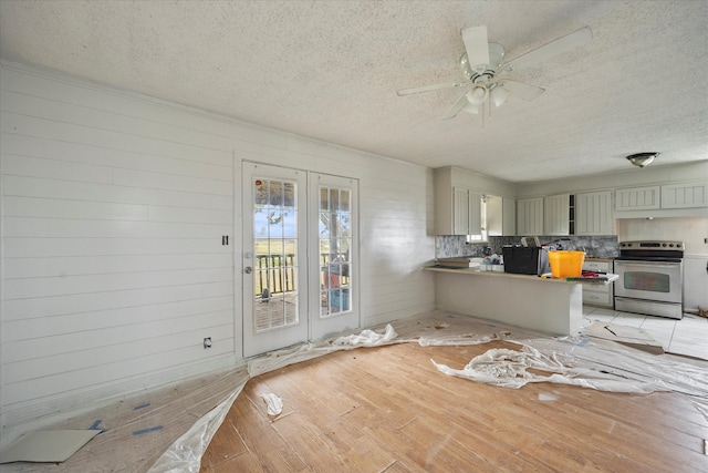 kitchen featuring electric stove, kitchen peninsula, light wood-type flooring, a textured ceiling, and ceiling fan