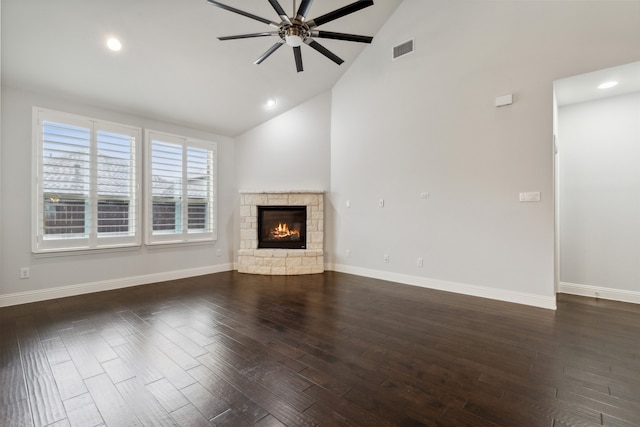 unfurnished living room with ceiling fan, a stone fireplace, dark wood-type flooring, and high vaulted ceiling