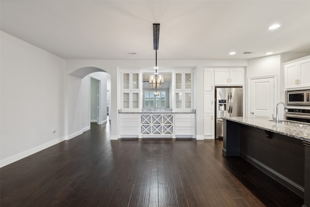 kitchen featuring hanging light fixtures, light stone countertops, stainless steel appliances, dark hardwood / wood-style floors, and sink