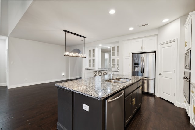 kitchen with appliances with stainless steel finishes, white cabinets, dark hardwood / wood-style flooring, a center island with sink, and sink