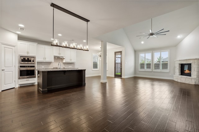 kitchen with a kitchen island with sink, appliances with stainless steel finishes, dark hardwood / wood-style floors, and a fireplace