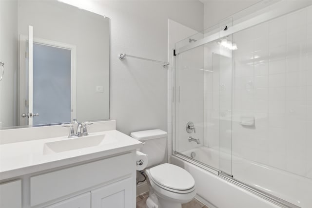 full bathroom with enclosed tub / shower combo, vanity, and toilet