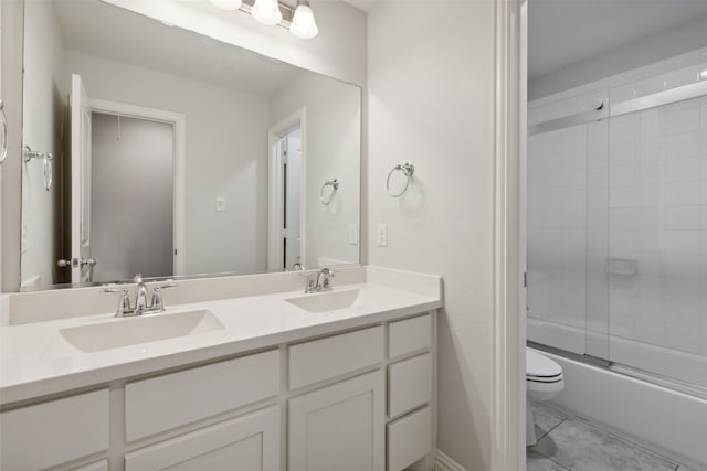 full bathroom featuring vanity, combined bath / shower with glass door, toilet, and tile patterned floors