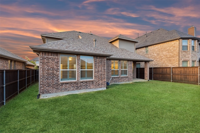 back house at dusk featuring a yard