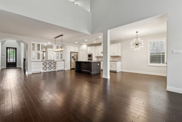 unfurnished living room featuring an inviting chandelier and dark hardwood / wood-style flooring