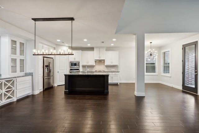 kitchen featuring white cabinets, dark hardwood / wood-style flooring, stainless steel appliances, decorative light fixtures, and a center island with sink