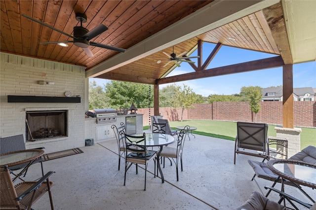 view of patio / terrace with grilling area, ceiling fan, and an outdoor brick fireplace