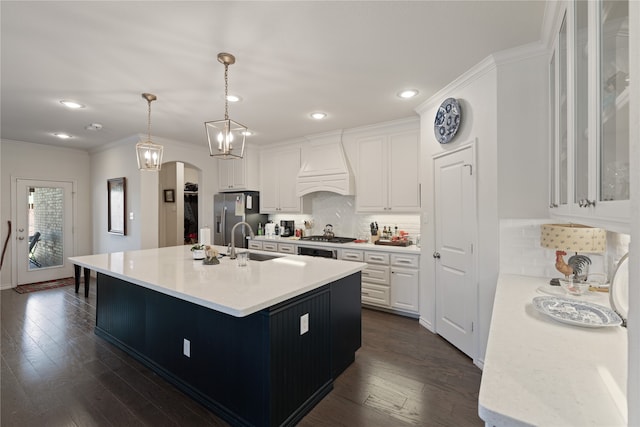 kitchen with white cabinetry, hanging light fixtures, dark hardwood / wood-style floors, a center island with sink, and custom range hood