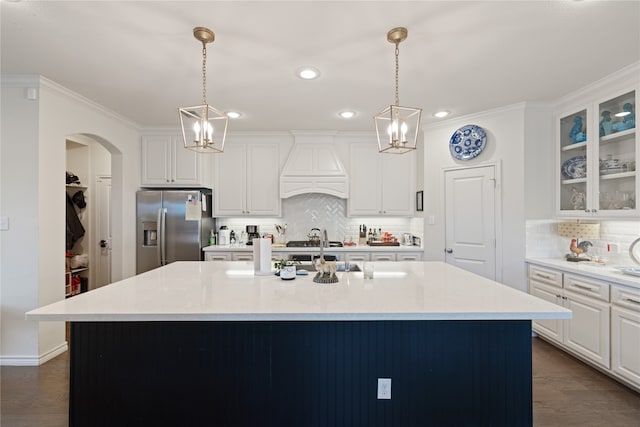 kitchen featuring a kitchen island with sink, pendant lighting, and stainless steel refrigerator with ice dispenser