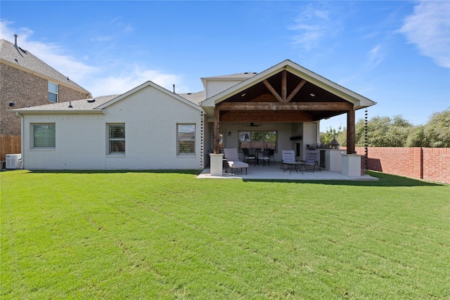 rear view of property with ceiling fan, a patio area, and a yard