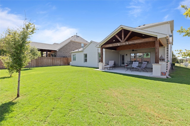 rear view of house featuring ceiling fan, a yard, and a patio