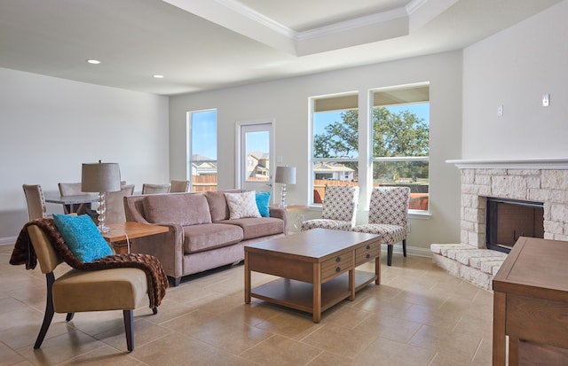 tiled living room featuring a fireplace, crown molding, a tray ceiling, and a wealth of natural light