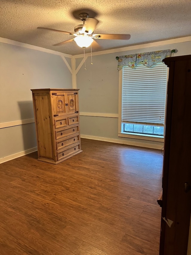 empty room with a textured ceiling, crown molding, dark hardwood / wood-style flooring, and ceiling fan