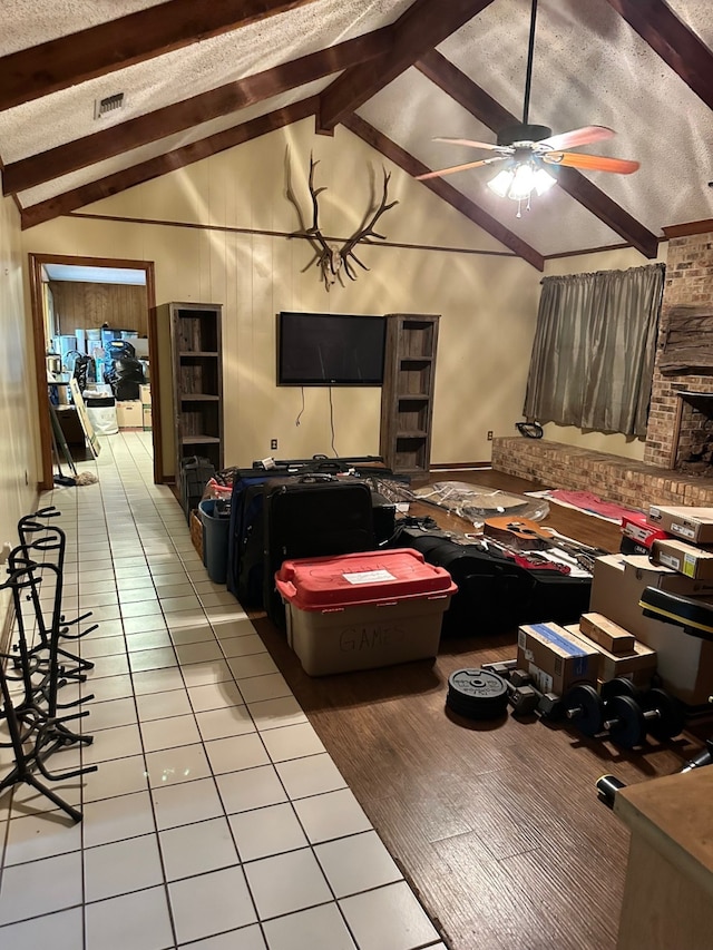 tiled living room with vaulted ceiling with beams, ceiling fan, and a textured ceiling