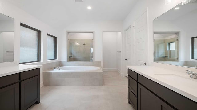 full bathroom with a bath, two vanities, a tile shower, a sink, and recessed lighting