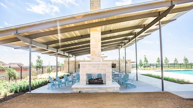 view of patio / terrace with an outdoor stone fireplace and fence