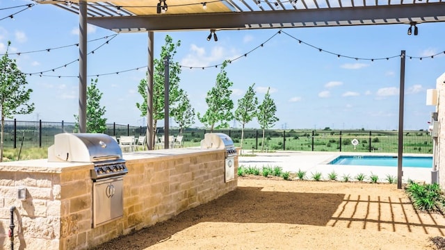 view of patio / terrace featuring exterior kitchen, a grill, a community pool, and fence