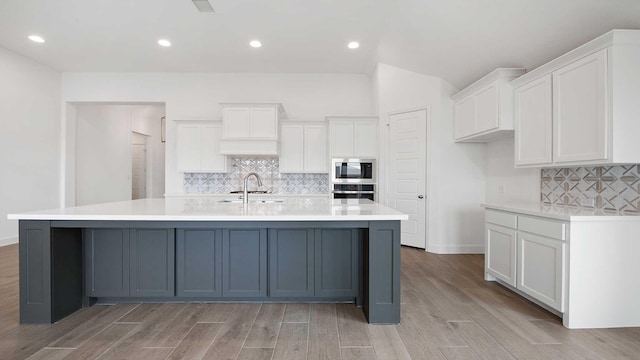 kitchen with a spacious island, stainless steel appliances, wood tiled floor, and white cabinets