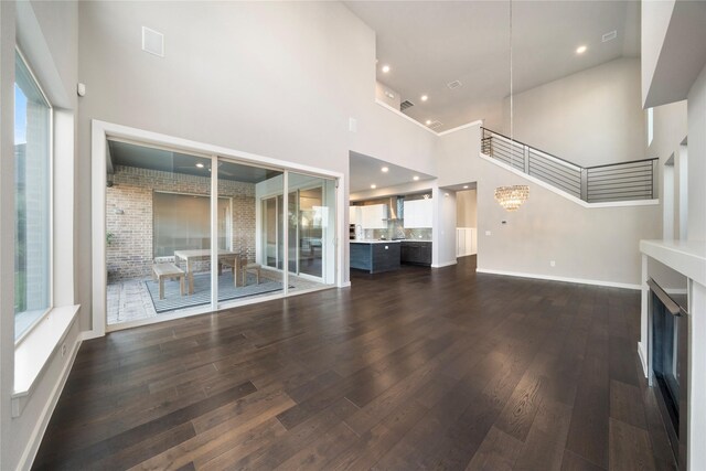 unfurnished living room featuring dark hardwood / wood-style flooring, a high ceiling, and a notable chandelier