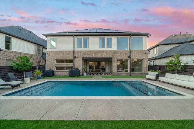 back house at dusk with a fenced in pool, an outdoor living space, a lawn, and a patio