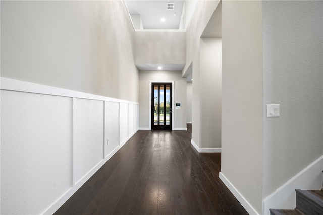 hallway featuring dark wood-type flooring and a high ceiling