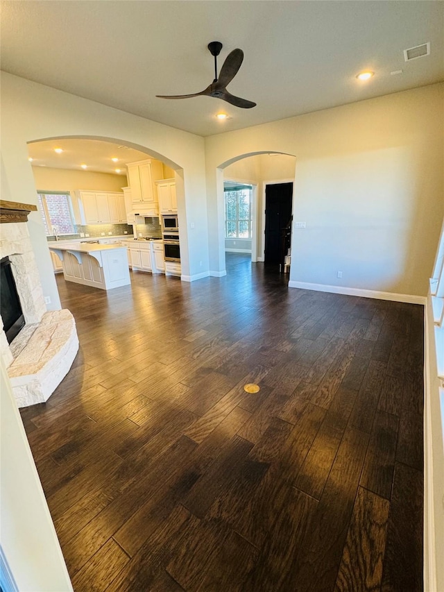 living area featuring dark wood-type flooring, a fireplace, visible vents, and baseboards