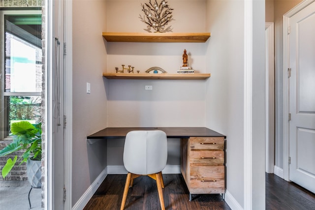 office with dark wood-style floors, built in desk, and baseboards