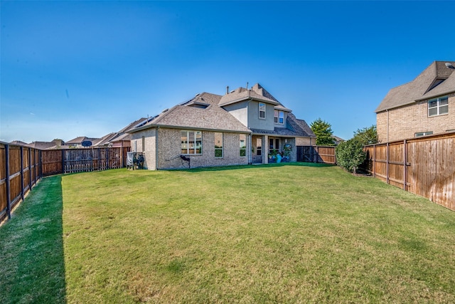 back of property featuring brick siding, a lawn, a fenced backyard, and stucco siding