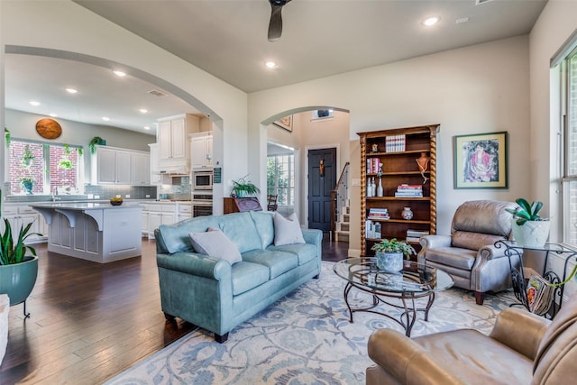 living room with a wealth of natural light, arched walkways, wood finished floors, and recessed lighting