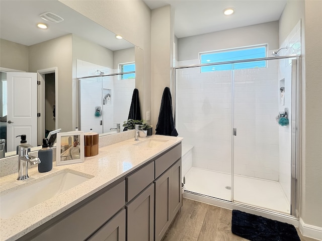 bathroom featuring wood-type flooring, a shower with door, and vanity