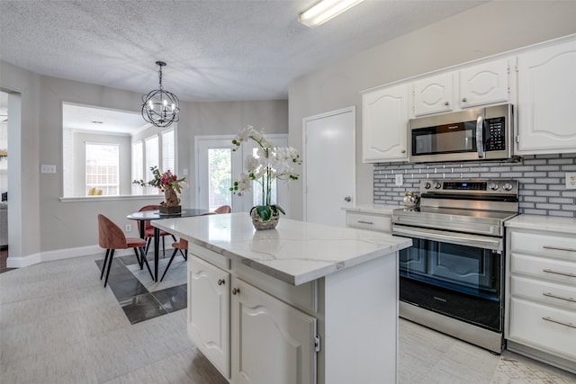 kitchen featuring hanging light fixtures, white cabinets, backsplash, stainless steel appliances, and a center island