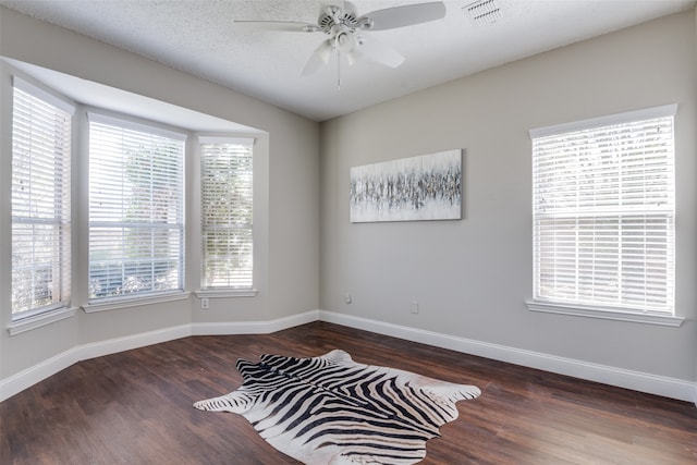 empty room featuring a textured ceiling, dark wood-type flooring, and ceiling fan